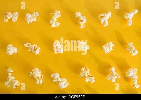 Nahaufnahme von Popcorn auf pastellgelbem Hintergrund. Kinokonzept mit vielen flauschigen Popcorn auf gelbem Retro-Hintergrund. Stockfoto