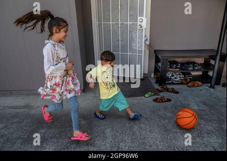 Sacramento, Kalifornien, USA. September 2021. Die Afghanen HASIBA, 8, und ihr Bruder ABDULLAH, 4, improvisieren mit einem Basketball, während sie vor der Wohnung eines Cousins in demselben Komplex Fußball spielen, in dem sie jetzt in Sacramento leben. Hesiba, die in Sacramento die Schule fortsetzen wird, sagte, dass sie bei der Strafverfolgung arbeiten möchte, wenn sie aufwächst. „Ich mag die Polizei“, sagte sie mit einem großen Lächeln. (Bild: © Renee C. Byer/Sacramento Bee/ZUMA Press Wire) Stockfoto