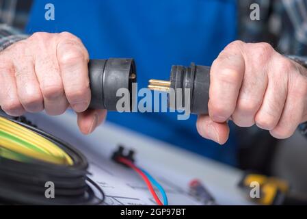 Elektroinstallateur hält Elektrostecker in der Hand Stockfoto