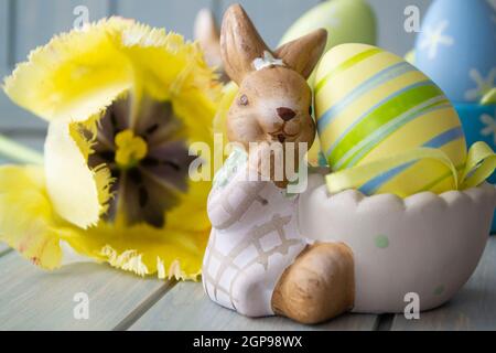 Osterhintergrund gelbe Tulpen auf Holztisch, Kaninchen mit Eiern aus nächster Nähe Stockfoto