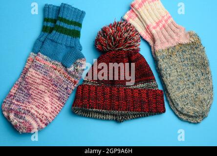 Warme bequeme Stricksocken und Strickmütze auf blauem Hintergrund, Draufsicht Stockfoto