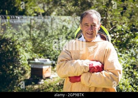 Kaukasischer älterer Mann in Imkeruniform und mit Blick auf die Kamera Stockfoto