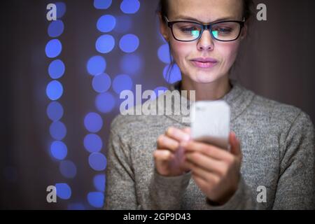 Junge Frau benutzt ihr Handy zu Hause Stockfoto