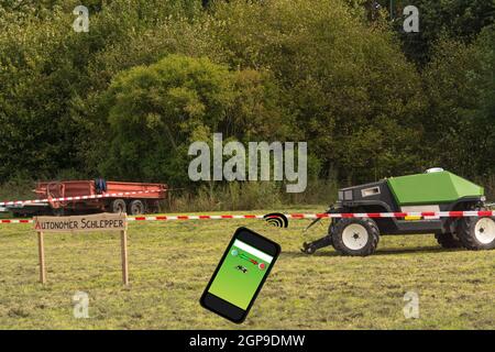 Autonomer Traktor auf dem Feld. Holzschild mit Inschrift in deutschen autonomen Traktor. Smart Farming und digitale Transformation in der Landwirtschaft. Stockfoto