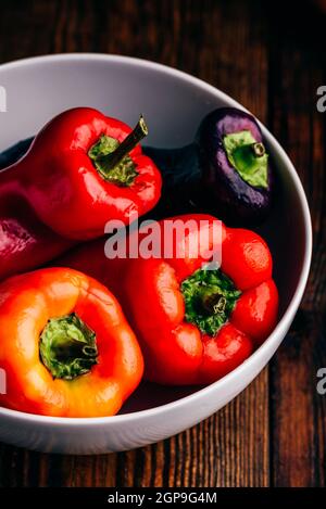 Bunte, frische Paprika in einer Schüssel auf einem Holzhintergrund Stockfoto