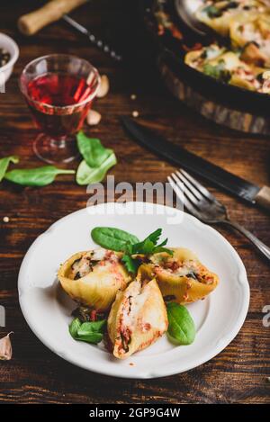 Gebackene Jumbo Shells Pasta gefüllt mit Hackfleisch, Spinat und Käse auf weißem Teller Stockfoto