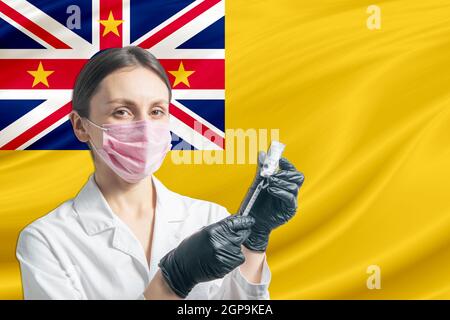 Ärztin bereitet die Impfung vor dem Hintergrund der Niue-Flagge vor. Impfkonzept Niue. Stockfoto