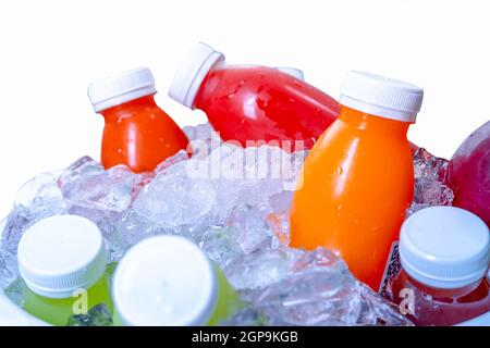 Bio kaltgepresste rohe Gemüse- und Fruchtsaftflasche in zerkleinertem Eiskübel auf weißem Hintergrund. Gesundes Getränk. Trendiges Saftgetränk. Entgiften Sie Saft Stockfoto