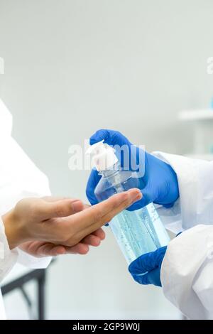Epidemiologische Forscher in Virusschutzkleidung waschen Hände mit Alkohol Gel vor Beginn des Experiments in einem wissenschaftlichen Labor. Hy Stockfoto