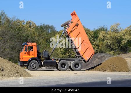 Die Dump Truck entlädt Schutt. Der Stapler gedumpten die Ladung. Sand und Kies. Bau von Straßen. Stockfoto