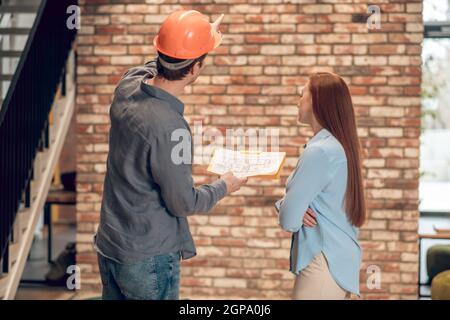 Rückansicht des Mannes mit Bauplan und der Frau Stockfoto
