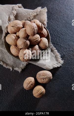 Walnüsse auf einer Baumwollserviette auf dunklem Grund. Ganze Walnüsse. Natürliches Bioprodukt. Vertikales Foto. Draufsicht. Stockfoto