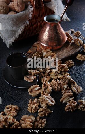 Geschälte Walnüsse auf dunklem Grund. Kaffee in einem kupfertürken. Der Kern der Walnuss. Naturprodukt. Vertikales Foto. Draufsicht. Stockfoto