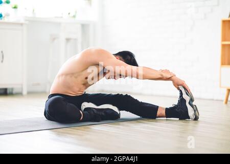 Muskulösen asiatischen jungen Mann tun Übungen auf dem Boden zu Hause Stockfoto