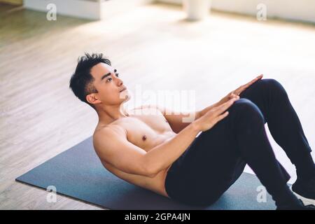 Muskulösen asiatischen jungen Mann tun Übungen auf dem Boden zu Hause Stockfoto