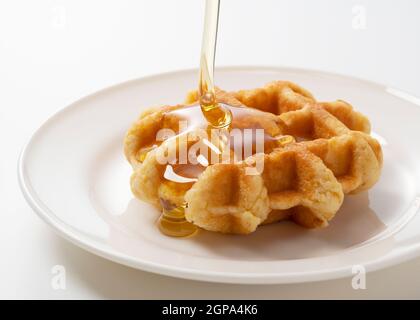 Tropfender Honig auf Waffeln auf weißem Hintergrund. Bildfoto Stockfoto