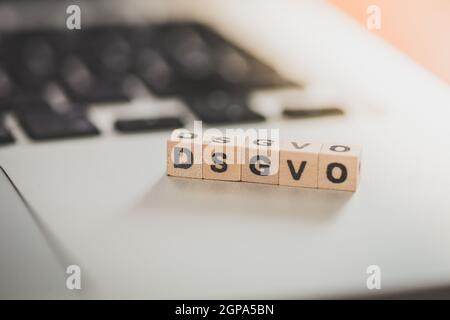 Holzwürfel mit den Buchstaben "DGSVO" für Datenschutzgrundverordnung liegen auf einem Laptop Stockfoto