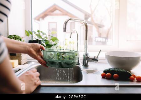 Frau waschen grüne Salatblätter für Salat in der Küche in Waschbecken. Hochwertige Fotos Stockfoto