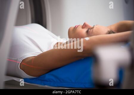 Hübsche, junge Frau, die durch eine computerisierte axiale Tomographie (CAT) Scan medizinische Test / Untersuchung in einem modernen Krankenhaus (Farbe getönten Bild; flach Stockfoto