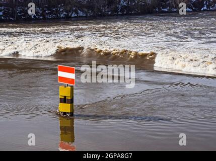 Staudamm der Saale in Halle mit Hochwasser und Schifffahrtsschildern Stockfoto