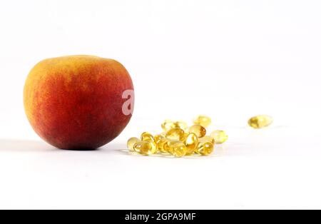 Vitamin-Pillen Kapseln zusammen mit Pfirsichfrucht freigesetzt gesunde Ernährung Vitamin c gut für das Immunsystem Stockfoto