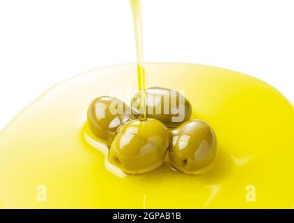 Der Moment, in dem Olivenöl über Oliven gegossen wird, die auf weißem Hintergrund stehen Stockfoto