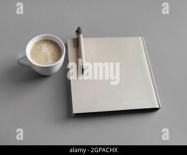 Geschlossene Broschüre, Kaffeetasse und Stift auf grauem Papierhintergrund. Stockfoto