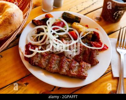 Gegrillter lula Kebab - Fleischgericht, mit Gemüse und Zwiebeln. Beliebtes orientalisches Gericht aus der Nähe Stockfoto