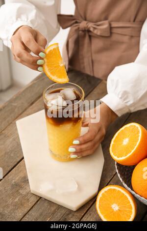 Frau dekorieren Glas leckeren Kaffee mit Orange, Nahaufnahme Stockfoto