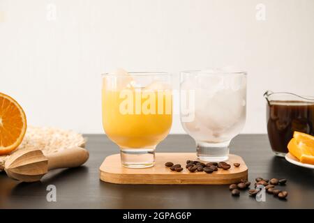 Ein Glas kalten Orangensaft und Kaffeebohnen auf dem Tisch Stockfoto