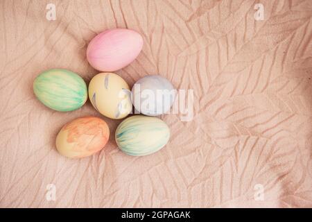 Schöne Aquarellfarben auf Ostereiern, die auf einem zarten rosa Stoff liegen. Osterkonzept Stockfoto