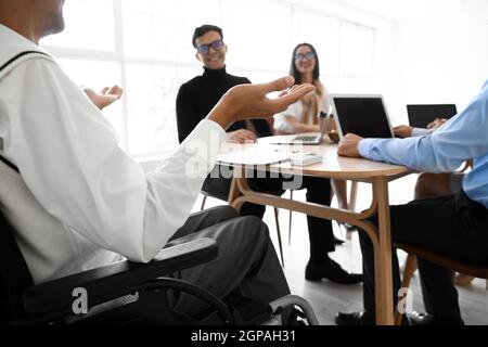 Mann im Rollstuhl, der im Büro vorgeführt wird Stockfoto