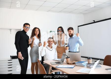 Glückliche junge Kollegen am Tisch im Büro Stockfoto