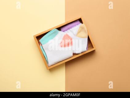 Holzkiste mit Socken auf farbigem Hintergrund Stockfoto