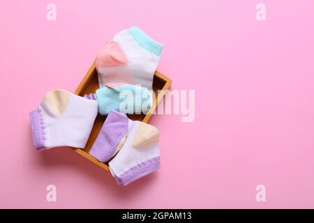Holzkiste mit verschiedenen Socken auf rosa Hintergrund Stockfoto