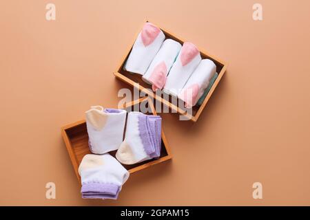Holzkisten mit Socken auf farbigem Hintergrund Stockfoto