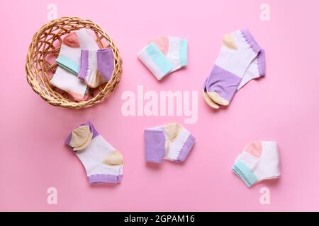 Korbkorb und verschiedene Socken auf farbigem Hintergrund Stockfoto