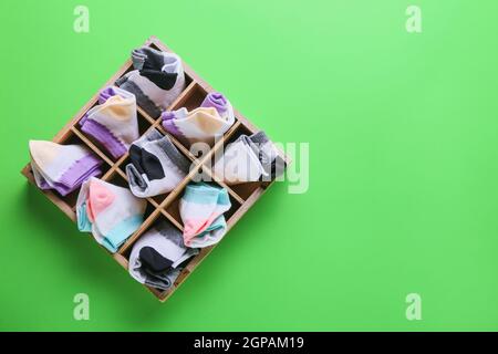 Organizer mit verschiedenen Socken auf grünem Hintergrund Stockfoto