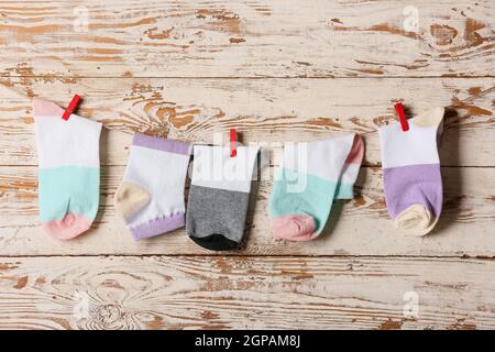 Viele verschiedene Socken hängen am Seil vor hellem Holzhintergrund Stockfoto