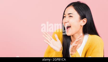 Happy Asian Portrait schön niedlich junge Frau stehend überrascht aufgeregt schreien offenen Mund zeigen Hand Studio Schuss isoliert auf rosa Hintergrund, Tha Stockfoto