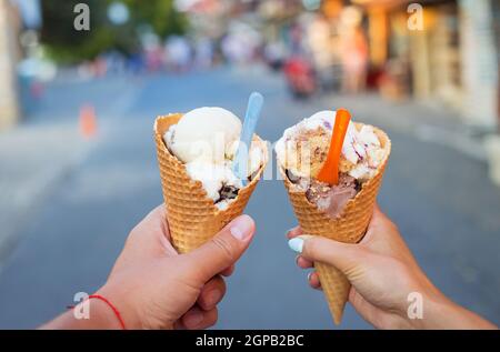 Schönes helles Eis mit verschiedenen Geschmacksrichtungen in den Händen von ein Paar. Stockfoto