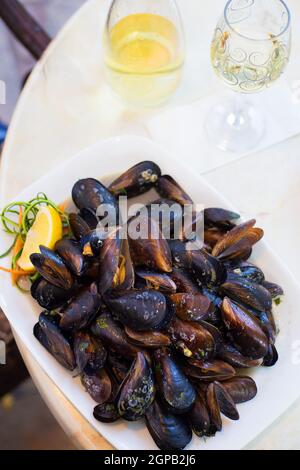 Muscheln in Schale mit Zitrone in Teller auf Tisch. Stockfoto