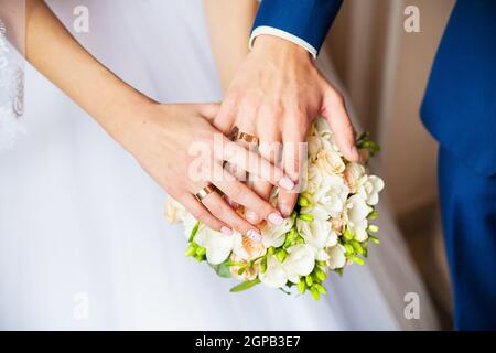 Eine neu weding Paar legen sie ihre Hände auf einer Hochzeit Bouquet zeigen Ihre Trauringe. Stockfoto