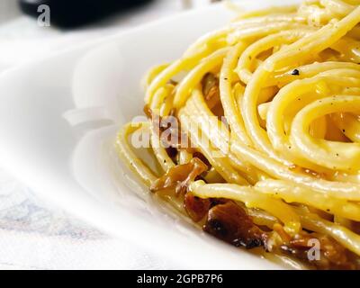 Detail der Spaghetti Carbonara in einem weißen Gericht serviert. Italienisches Essen. Berühmtes typisch römisches Rezept. Nahaufnahme von gekochten Spaghetti Stockfoto