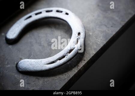 Draufsicht auf poliertes Hufeisen aus Stahl in natürlichem Licht auf einem Fensterschweller aus Marmor Stockfoto