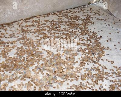 Münzen auf einem Betonboden. Werfen für Glück und Erfolg der Münzen in die heilige Stätte. Stockfoto