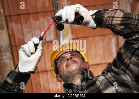 Elektriker bei der Arbeit ersetzt die Lampenfassung in einer elektrischen Wohnanlage. Bauindustrie, Energiesektor. Stockfoto