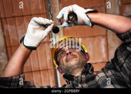 Elektriker bei der Arbeit ersetzt die Lampenfassung in einer elektrischen Wohnanlage. Bauindustrie, Energiesektor. Stockfoto