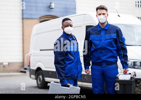 Elektriker Techniker Oder Klempner In Arbeitskleidung Und Gesichtsmaske In Der Nähe Van Stockfoto