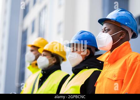 Fabrikingenieure Oder Bauarbeiter In Gesichtsmaske Stockfoto